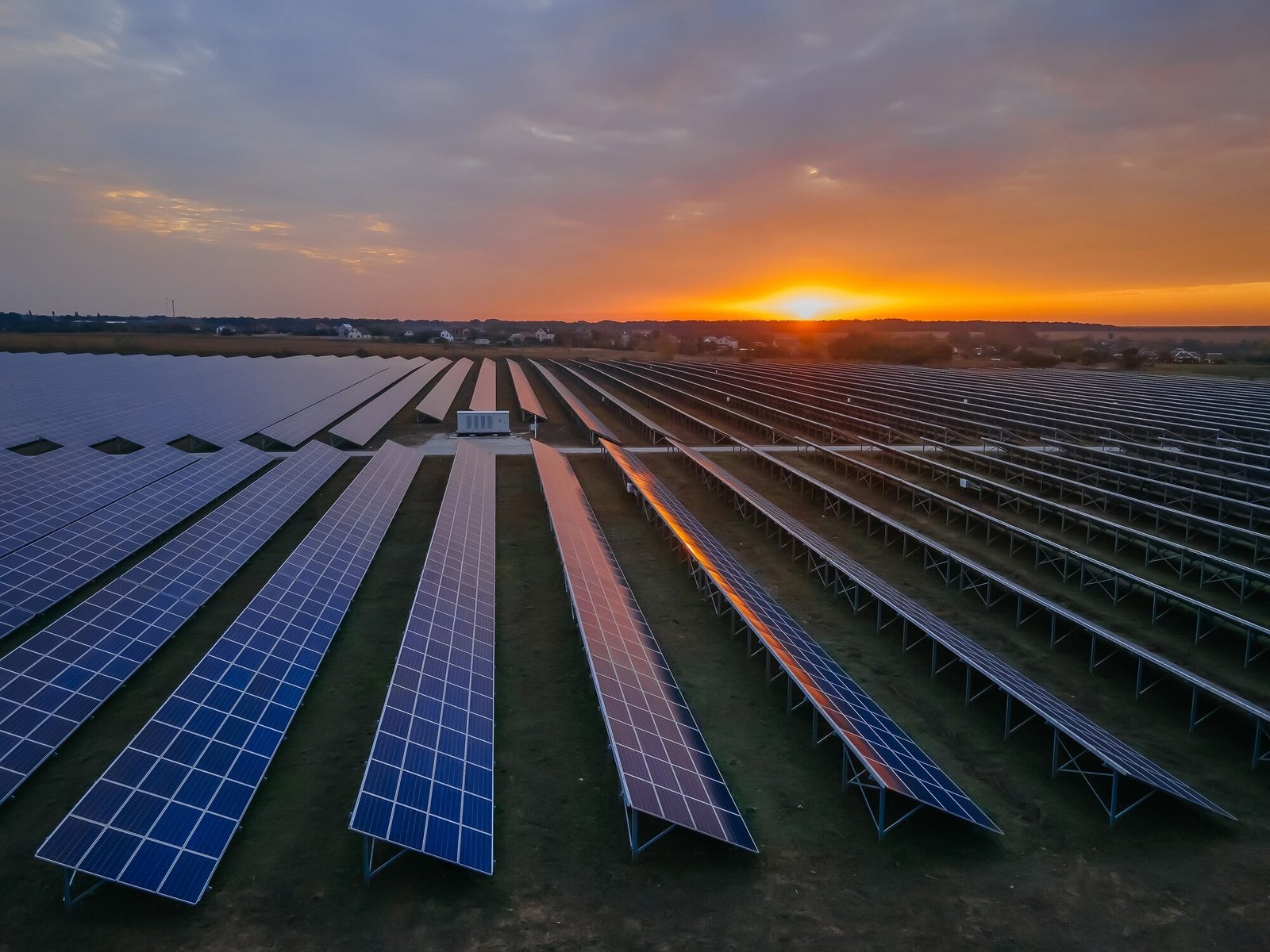 Aerial drone view into large solar panels at a solar farm at bright sunset. Solar cell power plants.